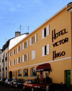 un gran edificio amarillo con un cartel. en Hotel Victor Hugo, en Dijon