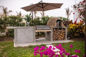 einem Grill im Freien mit einem Sonnenschirm und einem Stapel Holz in der Unterkunft Topara Hotel Boutique in San Vicente de Cañete