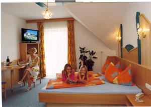 two girls laying on a bed in a room at Pension Drei-Mäderl-Haus in Unterlamm