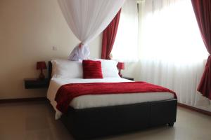 - une chambre avec un lit doté d'une couverture rouge et d'une fenêtre dans l'établissement Signature Hotel Apartments, à Jinja