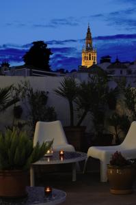 un patio all'ultimo piano con sedie e una torre dell'orologio di notte di Un Patio en Santa Cruz a Siviglia