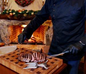 Ein Mann, der ein Stück Fleisch auf einem Schneidebrett zubereitet. in der Unterkunft En Dimitsani in Dimitsana