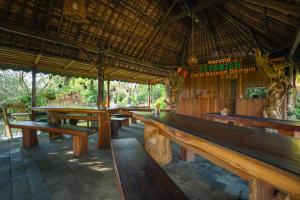 a restaurant with wooden benches and tables in it at The Tetamian Bali in Sukawati