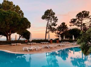 una piscina con sillas blancas y un complejo en PortoBay Falesia, en Albufeira