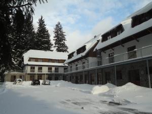 un parking couvert de neige en face d'un bâtiment dans l'établissement Penzion Dominik, à Železná Ruda