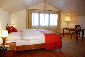 a bedroom with a bed and a desk and a window at Farbhaus by Kreuz Sachseln in Sachseln