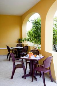 een restaurant met tafels en stoelen en twee ramen bij Affittacamere Casa del Sole in Cala Gonone