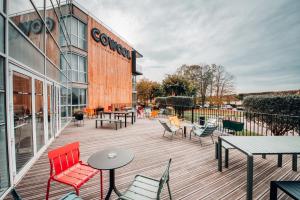 een houten terras met stoelen en tafels en een gebouw bij COWOOL Cergy in Cergy