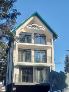 un edificio blanco alto con un letrero. en Отель MONBLAN, en Yablunytsya