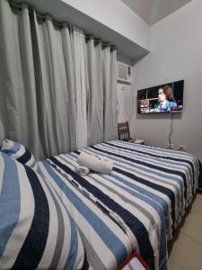 a bedroom with a bed with a tv in the background at Macks Awesome Place 204 NetflixFastWifi in Manila