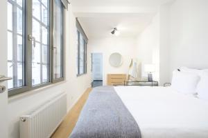 een witte slaapkamer met een groot bed en ramen bij Appartement design 3 chambres proximité Grand-Place Bruxelles in Brussel