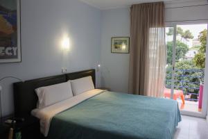 um quarto com uma cama e uma grande janela em Hotel Alexandra Sitges em Sitges