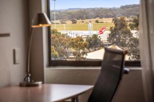 um quarto com uma secretária e uma janela com vista em Holiday Inn Melbourne Airport, an IHG Hotel em Melbourne