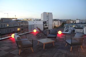 un patio all'ultimo piano con sedie, tavolo e luci di FINESTATE Coliving Mairie d'Issy a Issy-les-Moulineaux