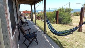 een veranda met 2 stoelen en een hangmat op een huis bij Agua Corazones in San Luis