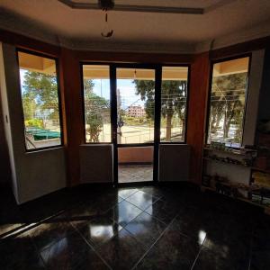 ein leeres Zimmer mit großen Fenstern und Straßenblick in der Unterkunft La Casita Feliz...!!! in Cochabamba