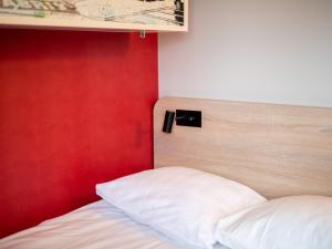 una camera da letto con una parete rossa e un letto con cuscini bianchi di Good Morning Jönköping a Jönköping