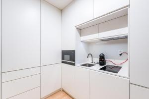 a kitchen with white cabinets and a sink at Door 65 - Historical Center Apartments in Porto