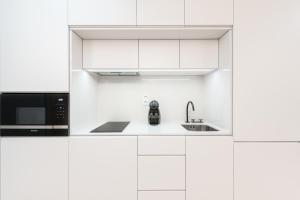 a white kitchen with a microwave and a sink at Door 65 - Historical Center Apartments in Porto