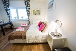 a bedroom with a bed with pink pillows and a lamp at Bled Apartments in Bled