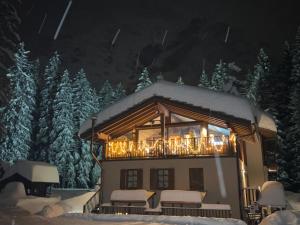 a house covered in christmas lights in the snow at WILDHOMES Wild Wolf Lodge in Courmayeur