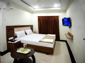 um quarto com uma cama, uma mesa e uma televisão em Hotel Sea Land em Kanyakumari