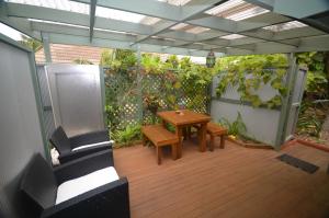 un patio con una mesa de madera y una valla con plantas en Cumberland Resort & Spa, en Burnt Pine