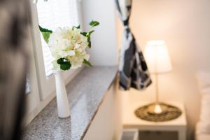 a white vase with flowers on a counter next to a lamp at Bled Apartments in Bled