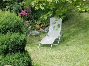 une chaise blanche assise dans l'herbe de la cour dans l'établissement Apartment Monte Rosa, à Delnice