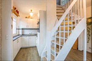 Una escalera blanca en una cocina junto a una cocina en Dachgeschosswohnung Scharbeutz mit Garten, en Scharbeutz