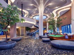 a lobby with a staircase and trees in a building at Grand Mercure Malang in Malang