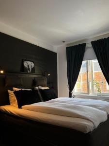 a bedroom with a large bed with black walls and a window at Hotell Dannegården in Trelleborg