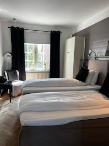 a bedroom with three beds and a window at Hotell Dannegården in Trelleborg