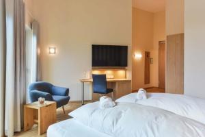 ein Hotelzimmer mit 2 Betten, einem Stuhl und einem Schreibtisch in der Unterkunft Hotel & Golfrestaurant Gut Wissmannshof in Staufenberg