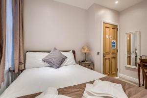 1 dormitorio con cama blanca y escritorio con lámpara en Central Belfast Apartments Harpers, en Belfast