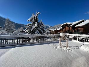 einen schneebedeckten Hof mit einem Haus und einem Baum in der Unterkunft Chalet Amour blanc in Les Houches