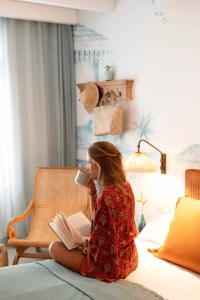 een vrouw op een bed die een boek leest bij Veranda Grand Baie Hotel & Spa in Grand Baie