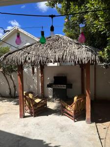 a thatch roof house with two chairs and a piano at Luna 39 in Oranjestad