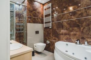 a bathroom with a tub and a toilet and a sink at Platinum Towers J&K in Warsaw