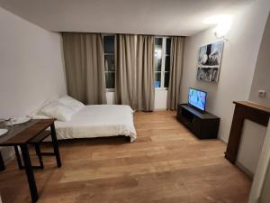 um quarto com uma cama, uma mesa e uma televisão em Studio cozy centre ville rdc em Bar-le-Duc