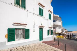 una calle con edificios blancos con persianas verdes en Private 2 Bed Apartment in Albufeira Old Town, en Albufeira