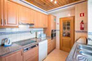 una cocina con armarios de madera y fregadero en Private 2 Bed Apartment in Albufeira Old Town, en Albufeira