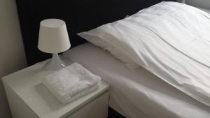 una cama blanca con una lámpara blanca en una mesita de noche en Hotel-Chao NL 24 hours open, en Utrecht