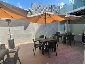 un patio avec des tables, des chaises et des parasols dans l'établissement Hotel Villas Santander, à Guatemala