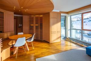 a dining room with a wooden table and white chairs at Terrazza su Sestriere Lux in Sestriere