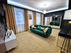 a living room with a green couch and some windows at Hotel Korona Spa & Wellness in Lublin