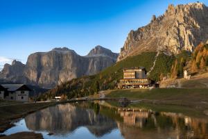 budynek na brzegu rzeki z górami w obiekcie Hotel Pordoi Passo Pordoi Vegetarian Hotel w mieście Canazei