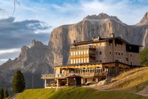 budynek na wzgórzu z górą w tle w obiekcie Hotel Pordoi Passo Pordoi Vegetarian Hotel w mieście Canazei