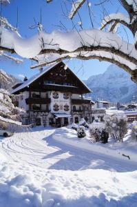 een gebouw bedekt met sneeuw voor een berg bij Hotel Spielmann in Ehrwald