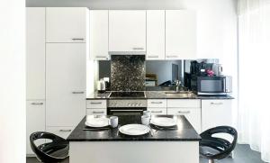 a kitchen with white cabinets and a black counter top at La Casa - comfortable - by PA in Luzern